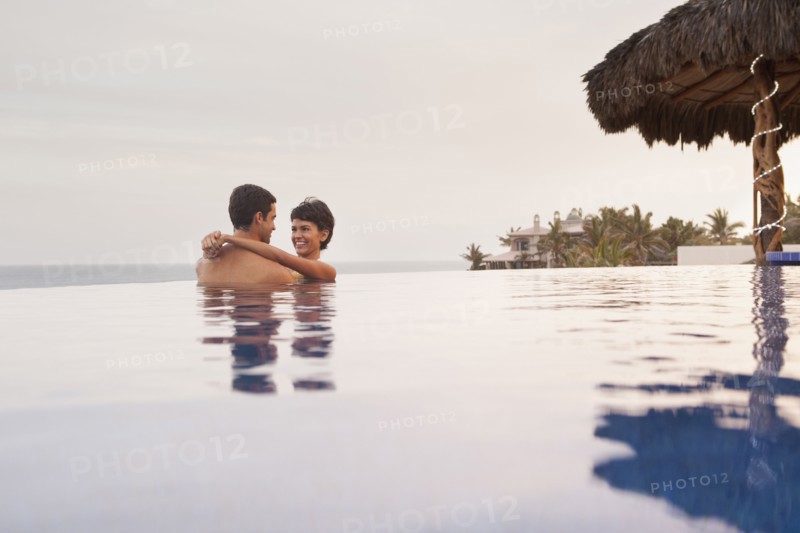 Hispanic couple hugging in swimming pool