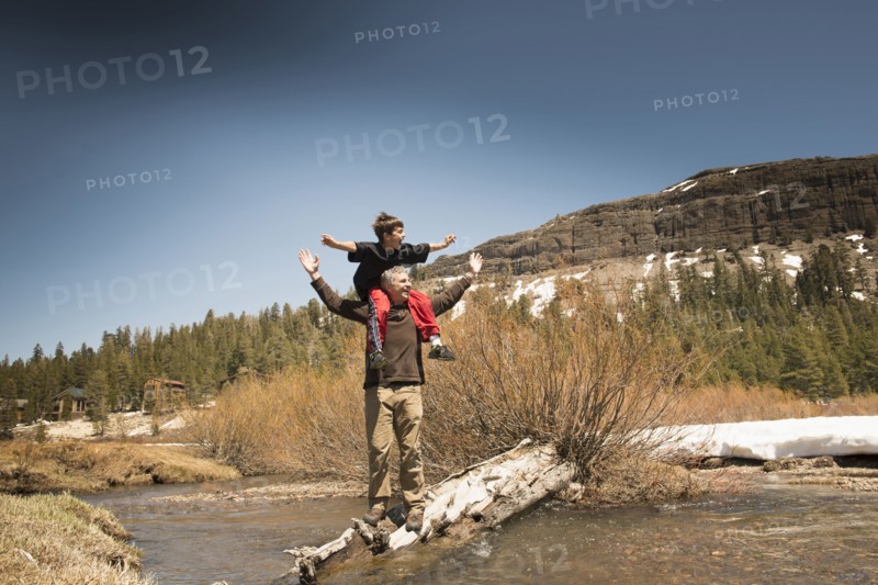 Boy sitting on father's shoulders in creek