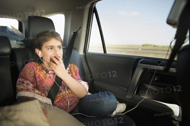 Mixed race girl eating apple in car