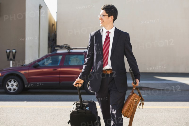 Hispanic businessman rolling luggage