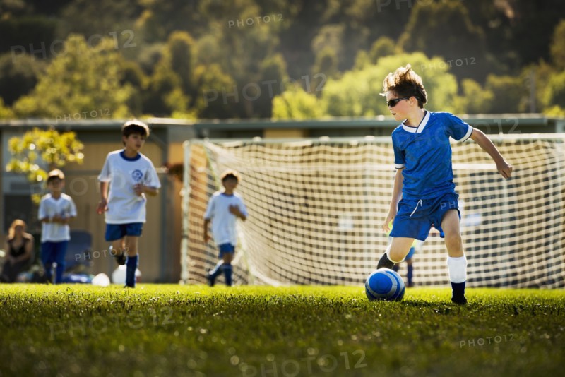 Caucasian boy playing soccer on pitch