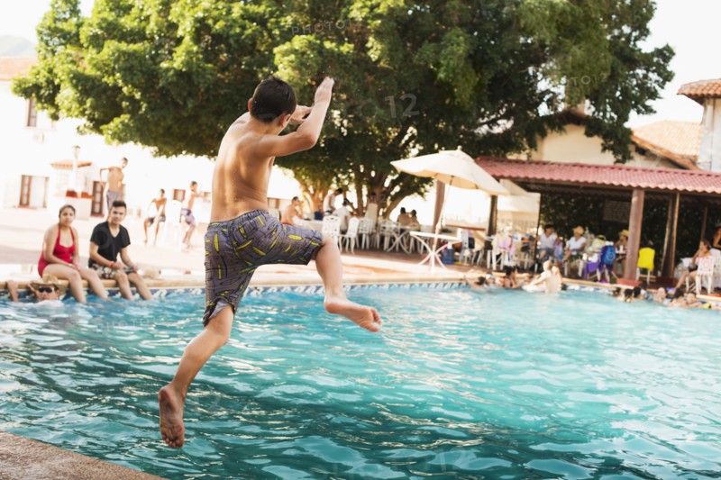 Mixed race boy jumping into pool