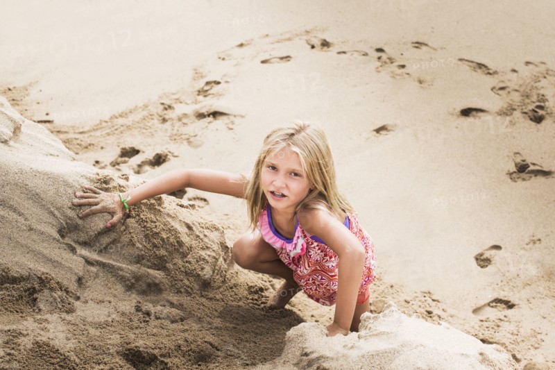 Caucasian girl climbing sand hill on beach
