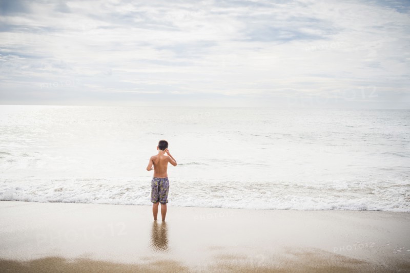 Hispanic boy standing in surf at beach