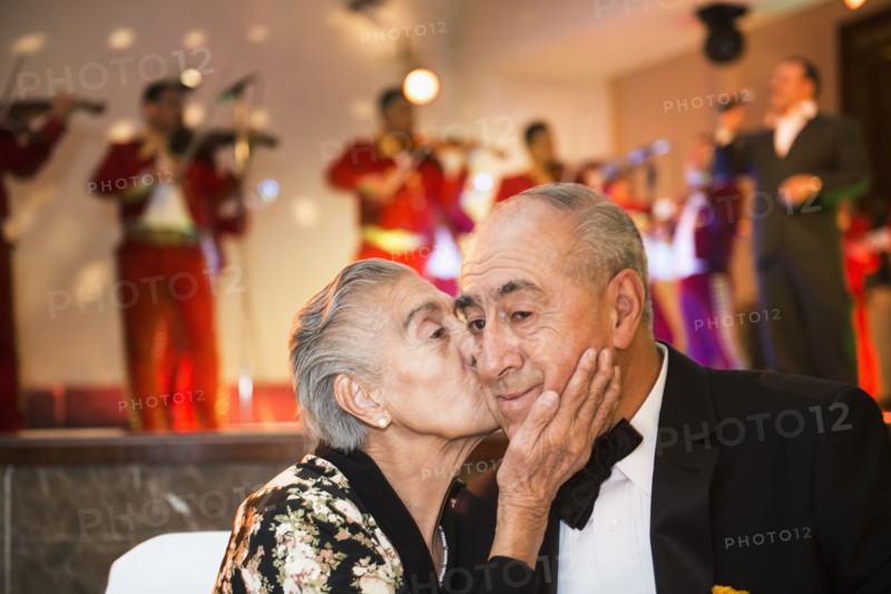 Hispanic couple kissing at wedding reception