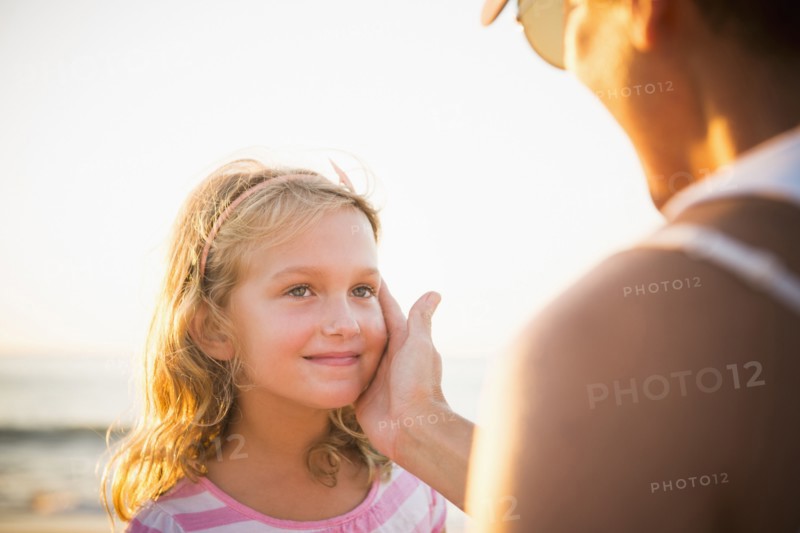 Mother cupping daughter's face on beach