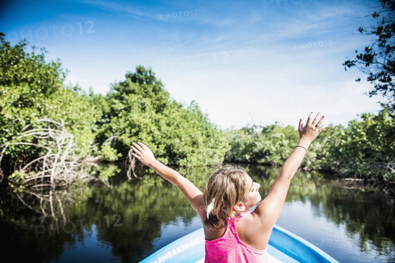 Mixed race girl sitting in canoe in still lake