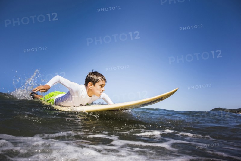 Mixed race boy surfing in ocean