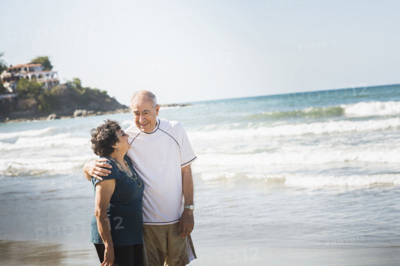 Hispanic couple hugging on beach