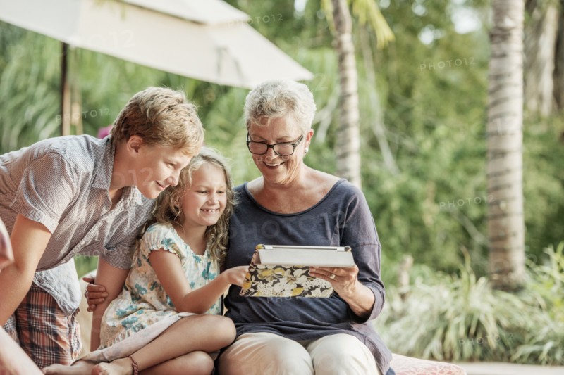 Older Caucasian woman and grandchildren looking at photo album