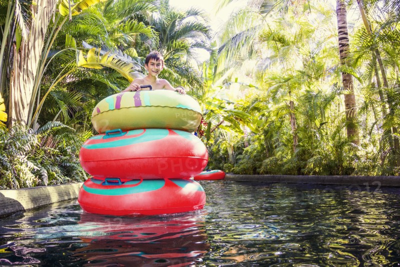 Mixed race boy playing in stacked inner tubes in pool