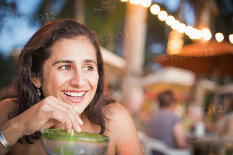 Hispanic woman drinking cocktail outdoors