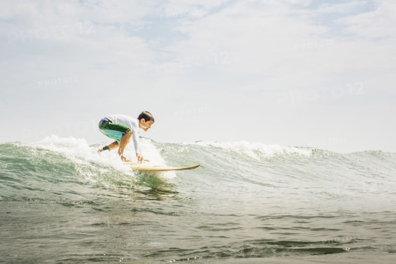 Mixed race boy surfing in waves