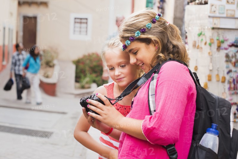 Girls looking at digital camera photographs on vacation