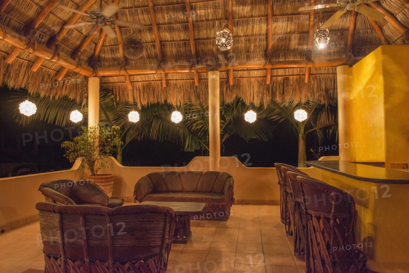 Sofas and chairs with bar on outdoor patio at night