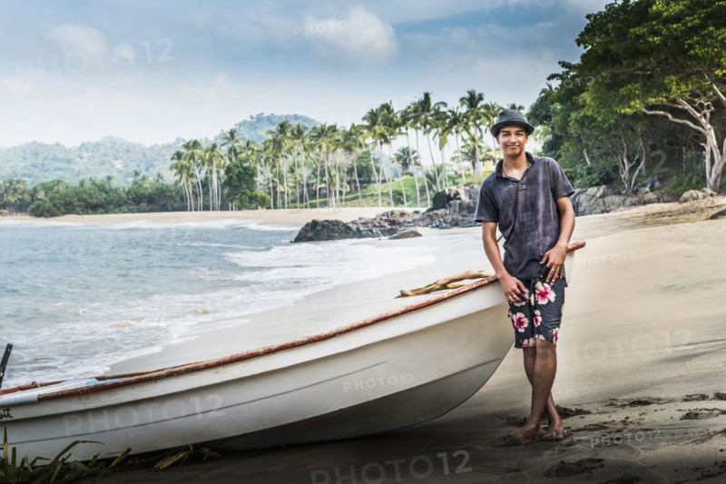 Hispanic man standing near boat on beach