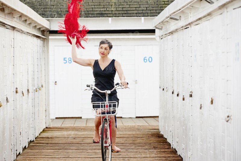 Older Caucasian woman riding bicycle on wooden dock
