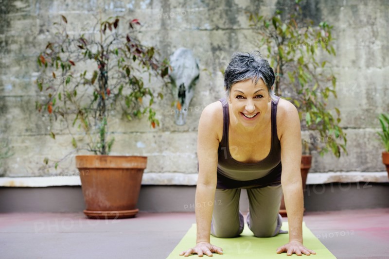 Older Caucasian woman practicing yoga in courtyard