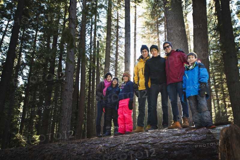 Family standing on log in remote forest