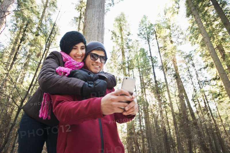 Hispanic teenage couple taking selfie in forest