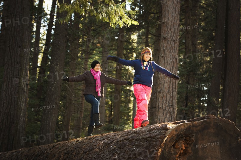 Children balancing on log in forest