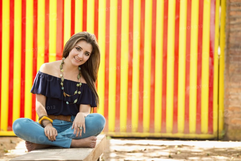 Hispanic woman sitting on stone wall