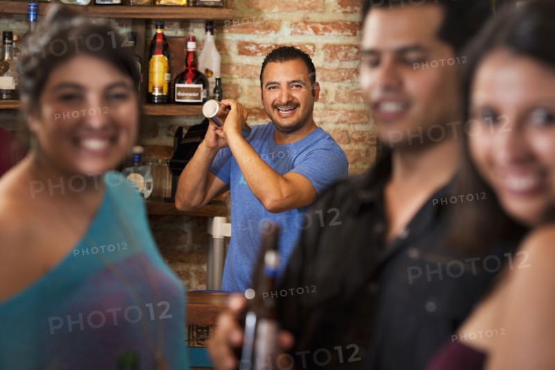 Hispanic bartender making drinks in bar