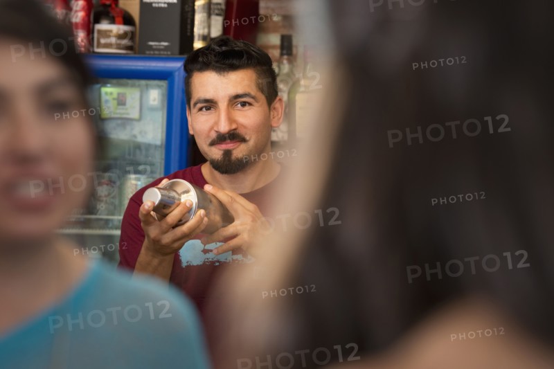 Hispanic bartender making drinks in bar