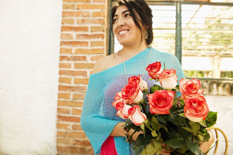 Hispanic woman carrying bouquet of roses outdoors