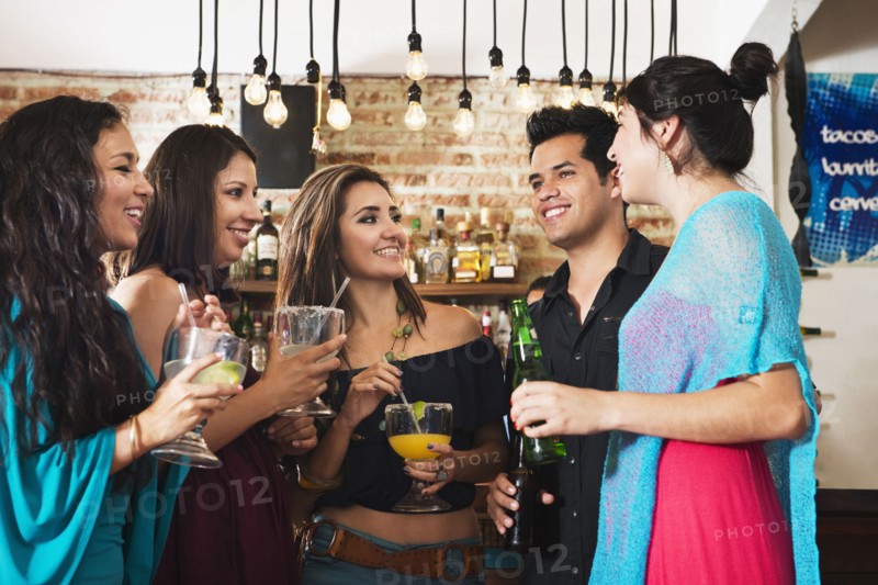 Hispanic friends having drink in bar