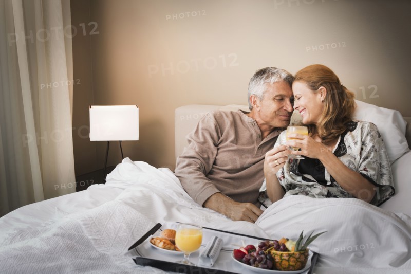 Smiling couple having breakfast in bed