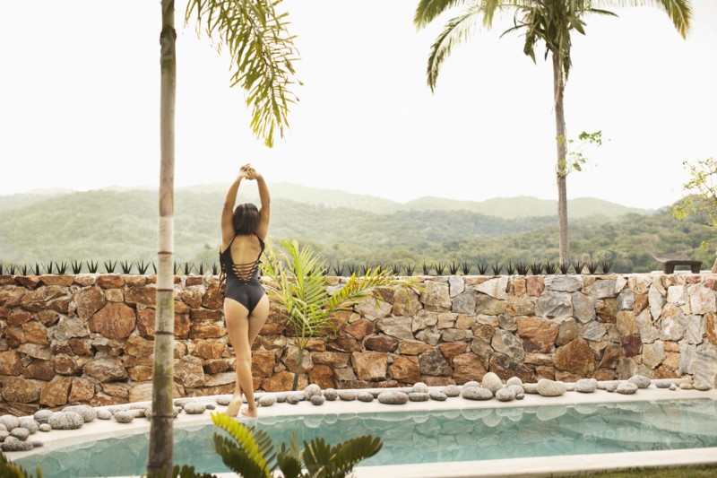 Hispanic woman stretching by swimming pool