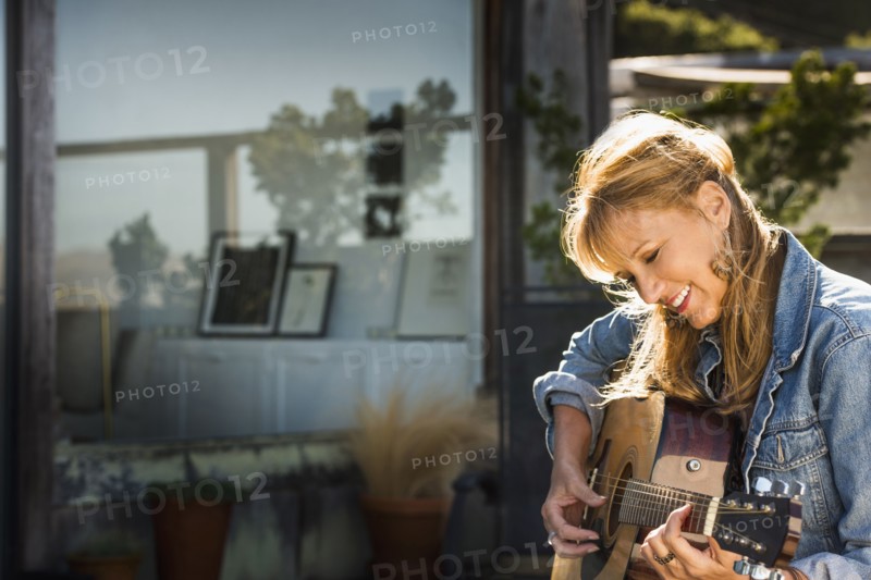 Caucasian woman playing guitar on porch