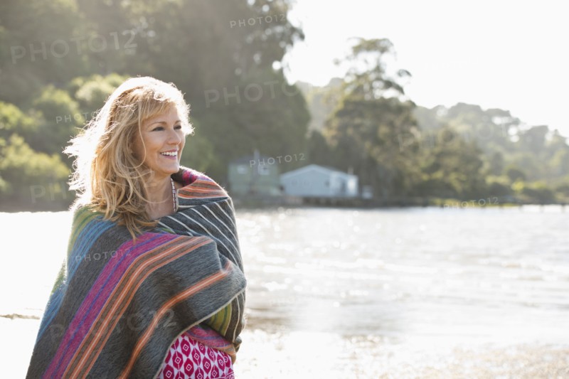 Caucasian woman wrapped in blanket on beach