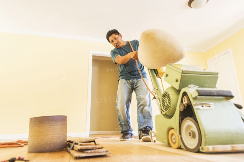 Hispanic man refinishing floors in new house