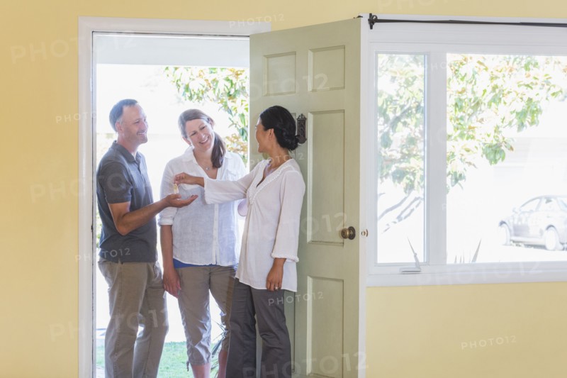 Real estate agent giving couple keys to new home