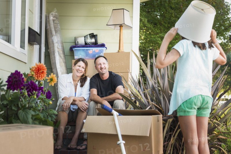 Caucasian parents watching daughter play outside house