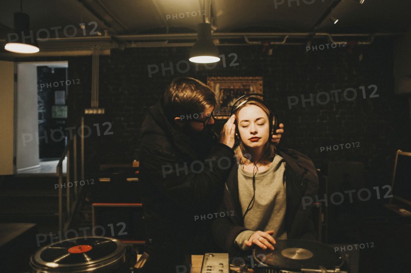 Caucasian dj holding headphones on woman