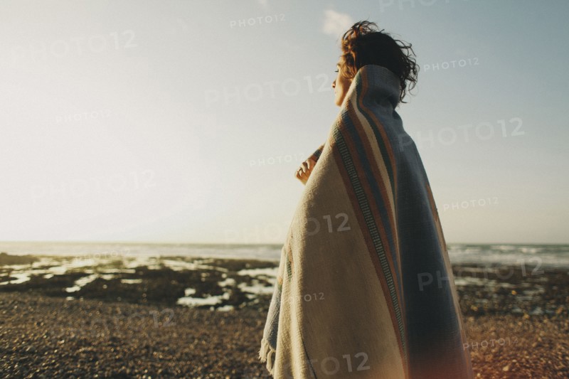 Caucasian woman wrapped in blanket at beach