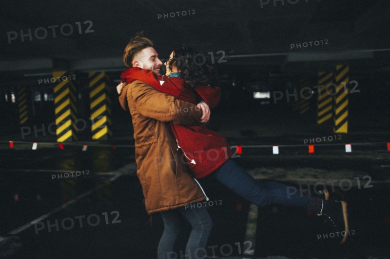 Caucasian couple hugging in parking garage