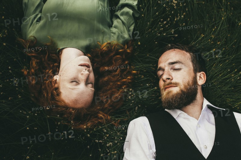 Caucasian couple laying in grass