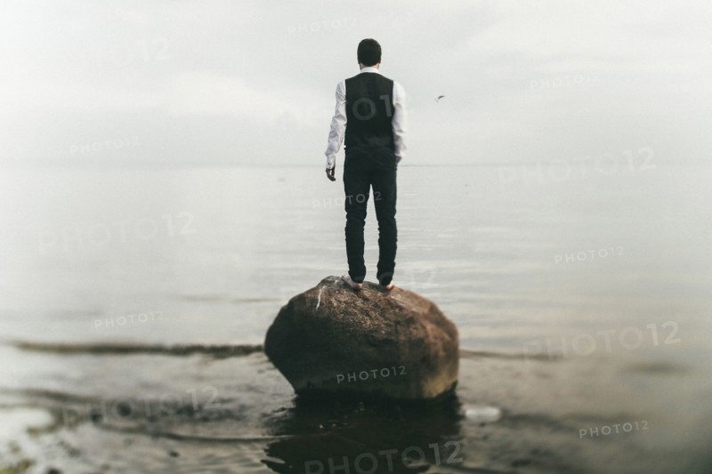 Caucasian man standing on rock at beach