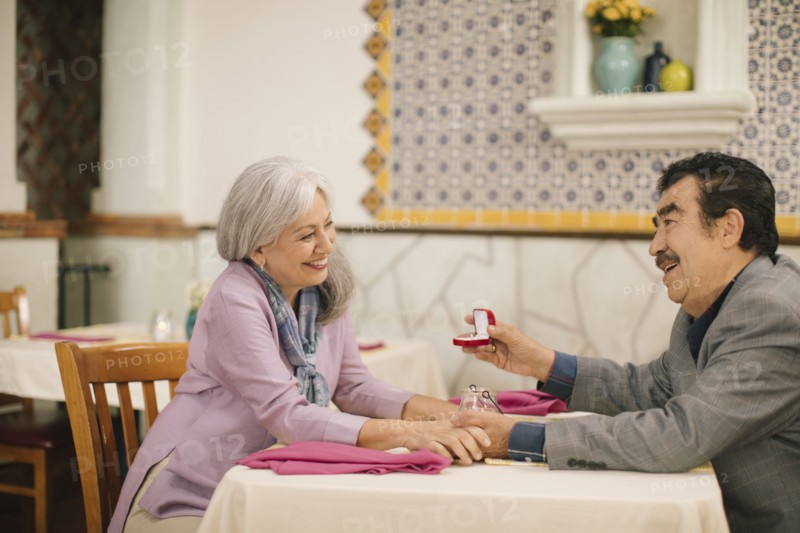 Older man proposing marriage to woman in restaurant