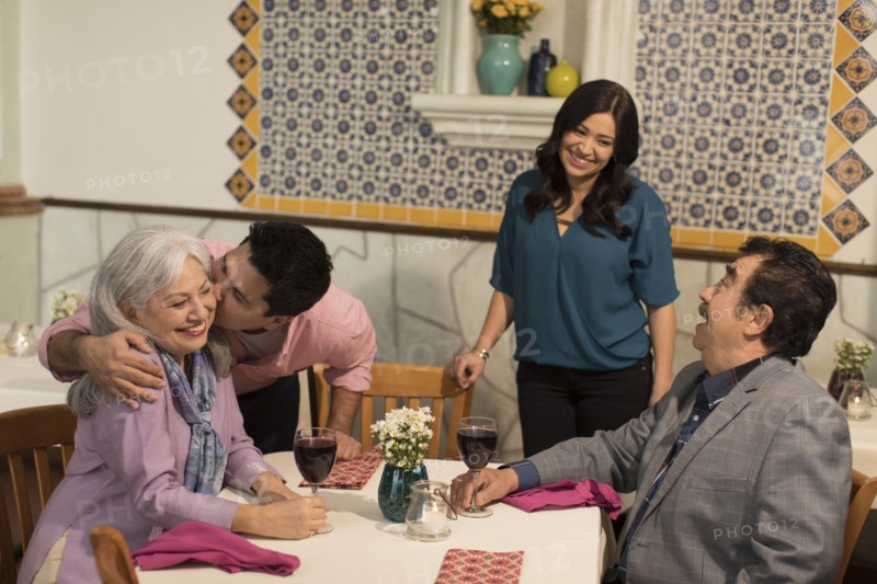 Younger couple greeting older couple in restaurant