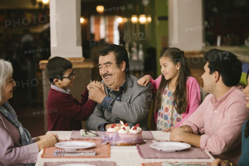 Family celebrating birthday or older man in restaurant