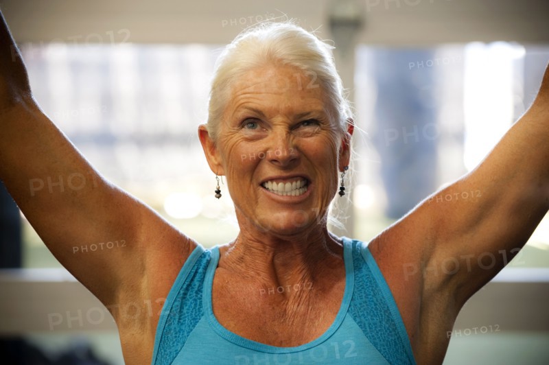 Grimacing older woman working out in gymnasium