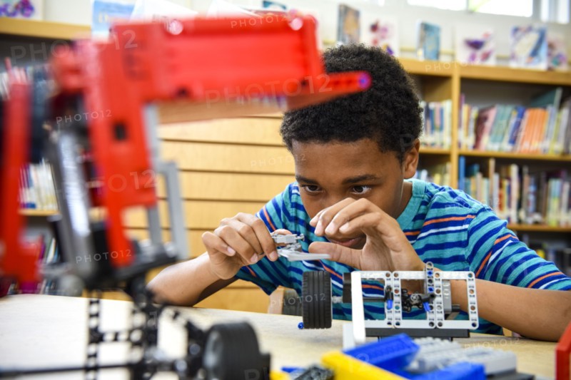 Boy assembling plastic blocks in library