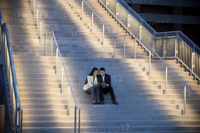 Couple sitting on staircase texting on cell phones