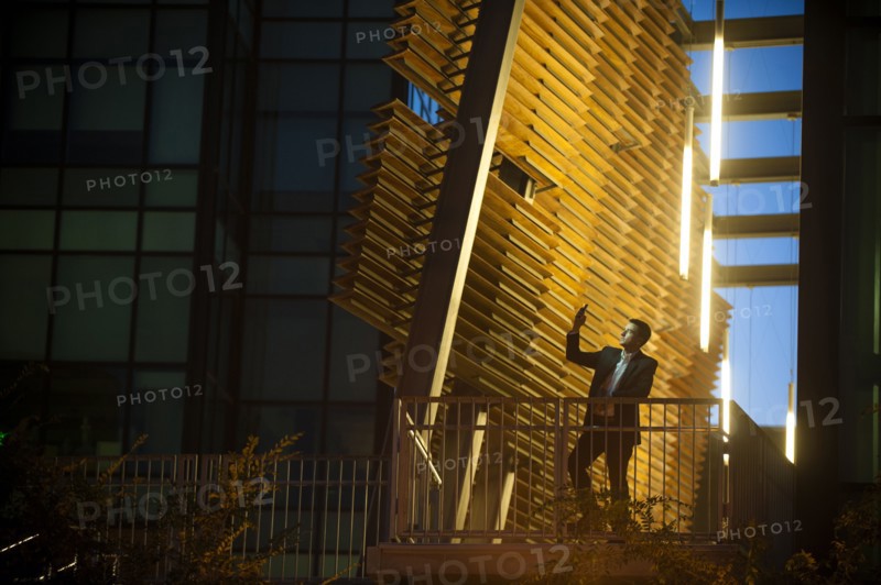 Businessman on balcony posing for cell phone selfie at night