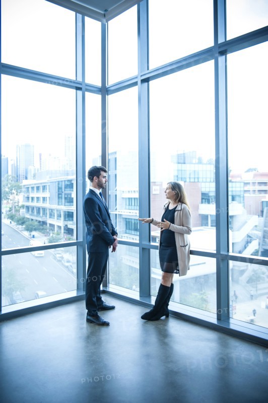 Businessman and businesswoman talking near window